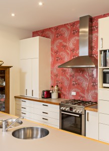 The new kitchen with high gloss cabinetry and Cole & Son wallpaper behind the stove.